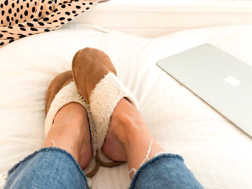 Macbook Air with girls feet wearing slippers on bed - she's procrastinating.